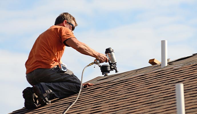 professional roofing service building contractor putting the asphalt roofing on a building